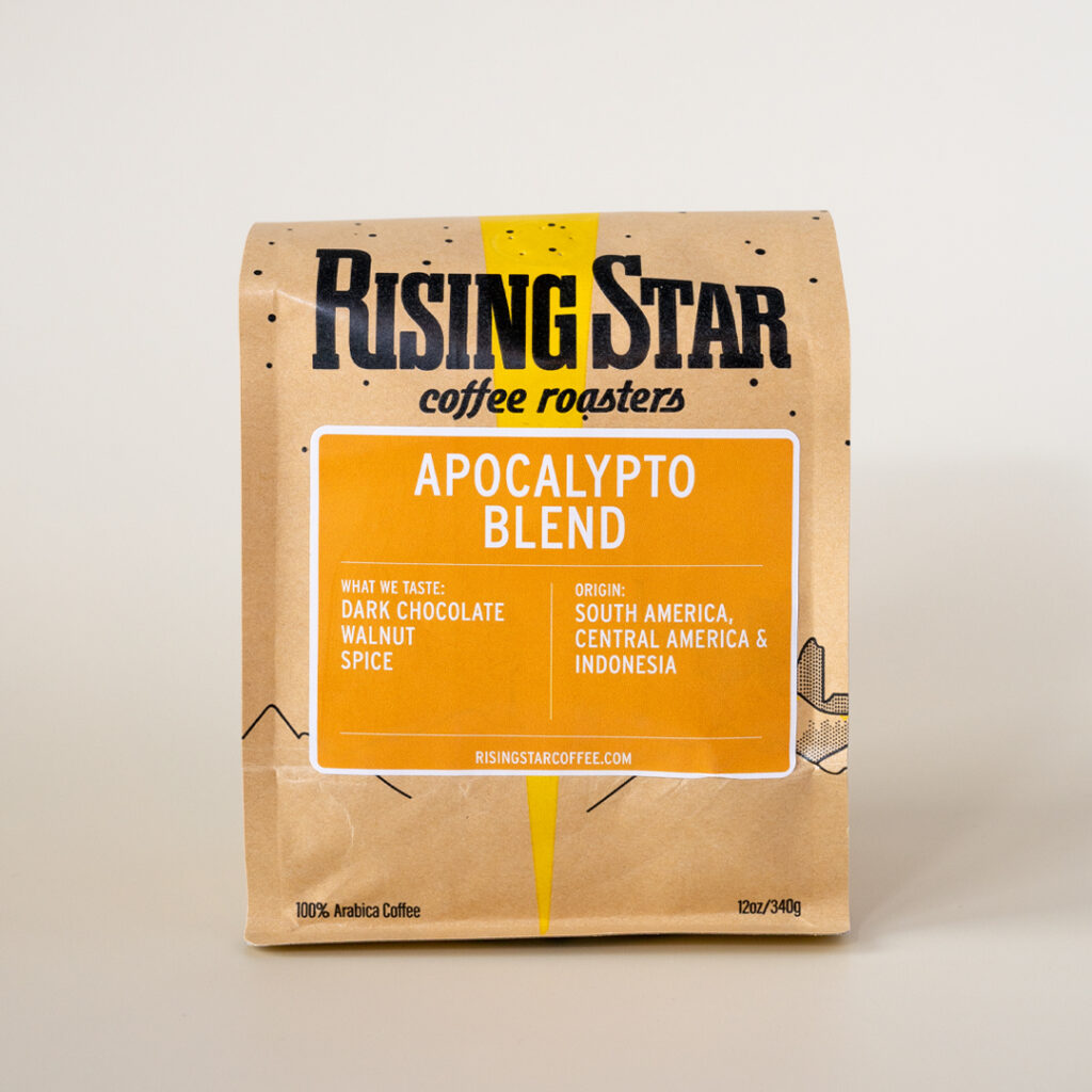A Rising Star Coffee bag with a deep yellow almost orange that reads Apocalypto Blend. This coffee is a blend of South American coffees, Central American Coffees, and Indonesian coffees. It has notes of Dark Chocolate, Walnut, and spices.