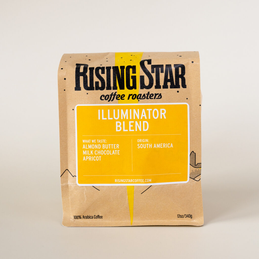 A Rising Star Coffee bag with a bright canary yellow label that reads "Illuminator Blend". This South American coffee with notes of Almond Butter, Milk Chocolate, and Apricot.
