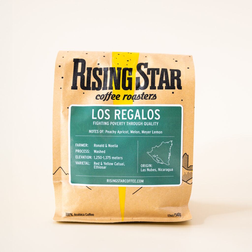 A Rising Star Coffee bag with a sage green label that reads "Los Regalos: Fighting Poverty Through Quality". This Nicaraguan coffee has notes of Peachy Apricot, Melon, and Meyer Lemon.