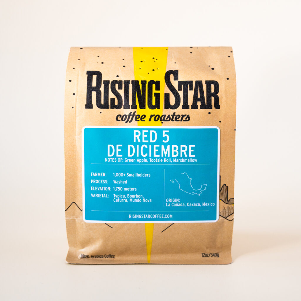 A bag of Rising Star Coffee with a turquoise label that reads "Red 5 De Diciembre". This Mexican coffee has notes of Green Apple, Tootsie Roll, and Marshmallow.