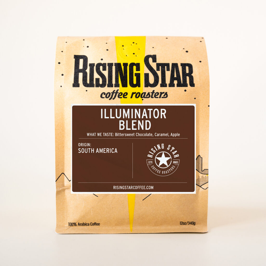 A 12-ounce bag of Rising Star Coffee Roasters Illuminator Blend. The brown bag features a yellow design with black speckles and bold black text reading “Rising Star coffee roasters.” A brown label in the center reads “Illuminator Blend” with tasting notes of bittersweet chocolate, caramel, and apple, and the origin listed as South America. The Rising Star logo and website appear at the bottom of the label.