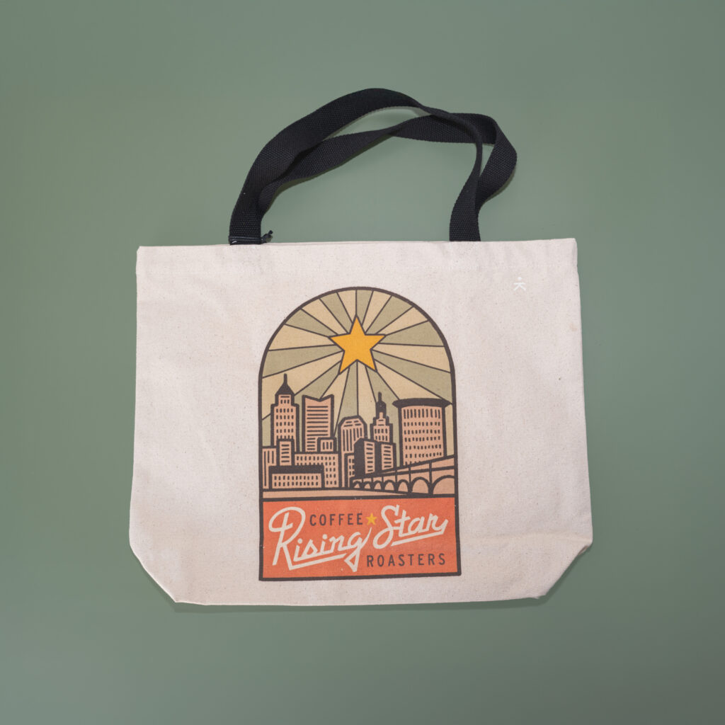 A canvas tote back with artwork that features downtown Cleveland and Rising Star Coffee script.