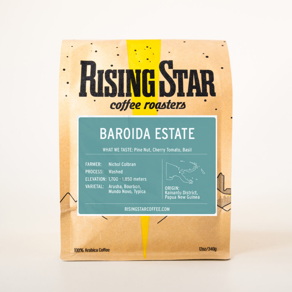A bag of Rising Star Coffee with a light blue label called Baroida Estate with notes of pine nuts, tomato, and basil from Papua New Guinea.
